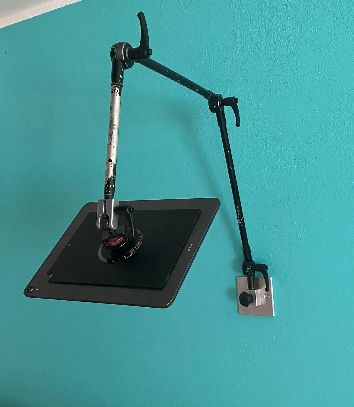 Eine Halterung für das Tablet an einer türkisfarbenen Wand.